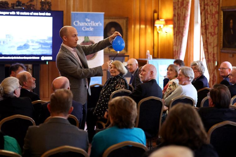 A lecturer giving a demonstration with a balloon to a full audience